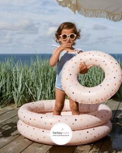 Mädchen im rosa Planschbecken mit Schwimmreifen